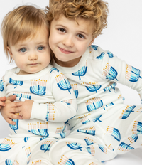 Child posing in a comfy Goodnight Hannukah print on Kids Unisex Pajamas Set made of 100% organic cotton