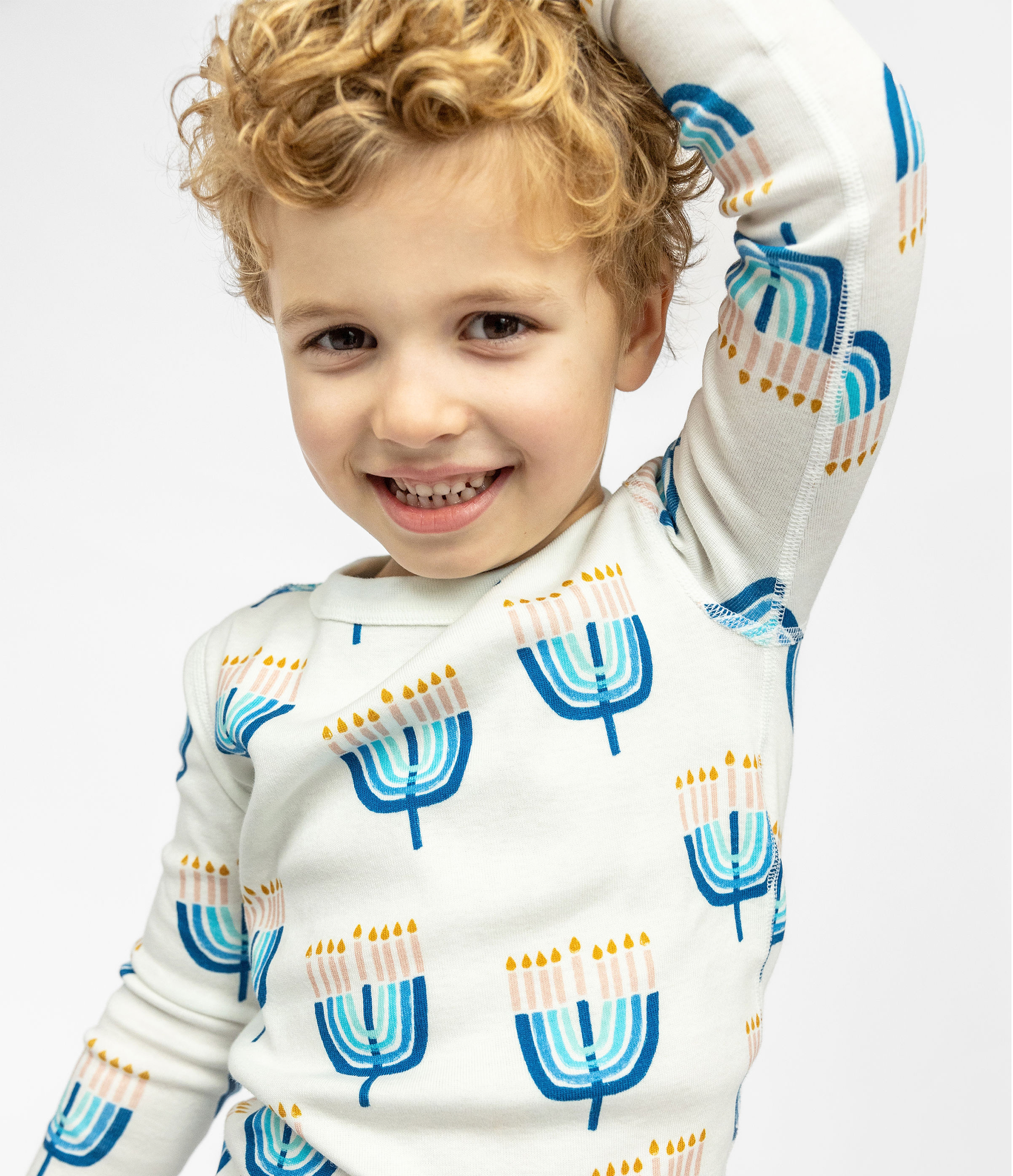 Child posing in a comfy Goodnight Hannukah print on Kids Unisex Pajamas Set made of 100% organic cotton