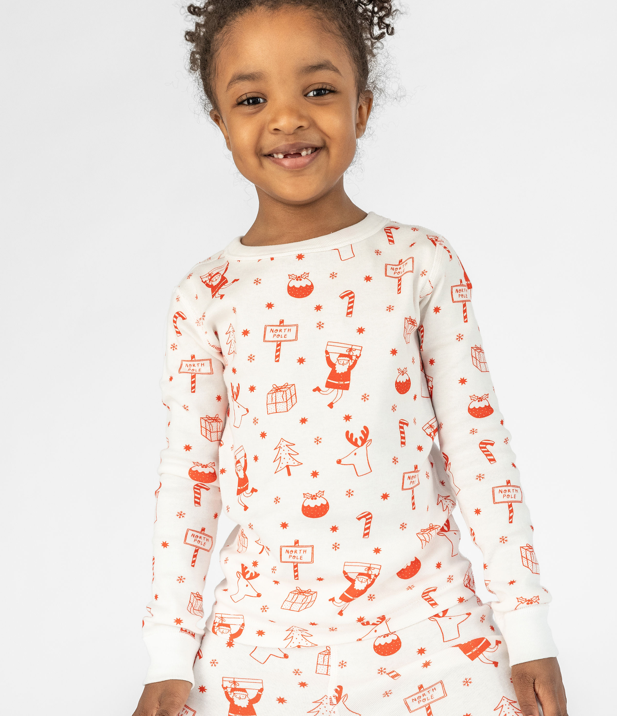 Cute 4 Year Old Girl with White with Fun Red North Pole-themed Graphics, Long Sleeves Top from the Long-john Pajama Set. Comfortable and Cozy Sleepwear for Kids. 100% Organic Cotton.