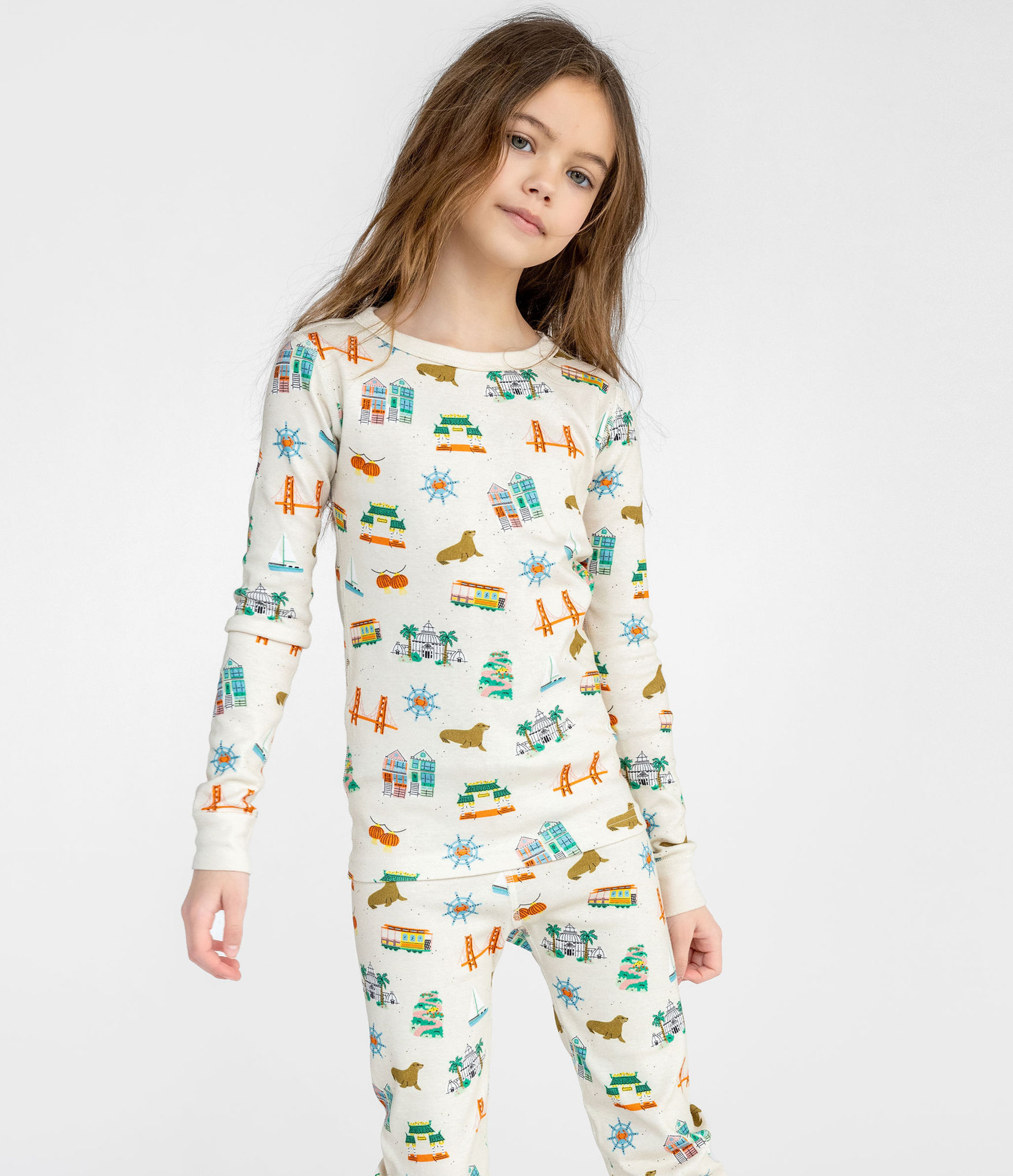 Adorable Young Girl with Off-White with Fun San Fransisco-themed Graphics, Long Sleeves Top and Pants, Comfortable and Cozy Sleepwear for Kids. 100% Organic Cotton. Long John Two-Piece Set.