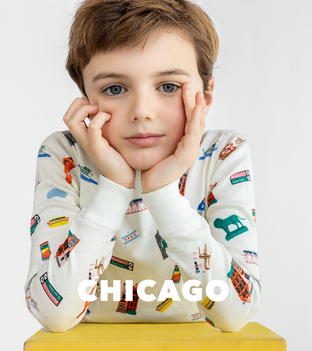 Boy slightly smiling resting his chin on his hands wearing Chicago printed pajama