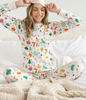 100% Organic Cotton pajamas featuring artist illustrated vintage ornaments.  Image shows a women enjoying the pajama set in bed.